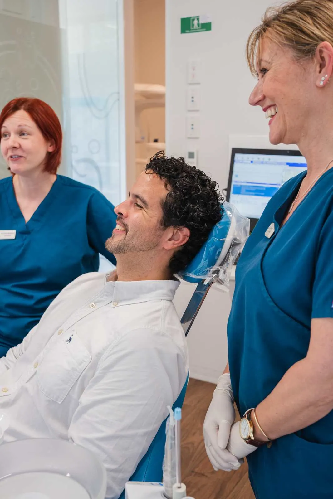 Dr Claire Mulquiney and a colleague talking with a patient in the chair